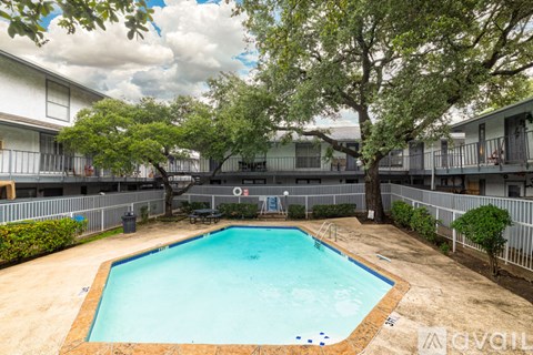 A swimming pool in a courtyard surrounded by trees and buildings.