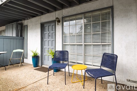 A patio with a blue chair, a yellow table, and a potted plant.