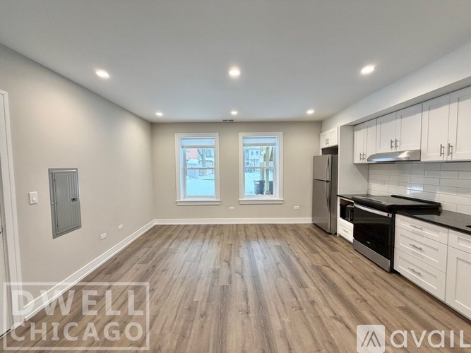 A kitchen with white cabinets and a wooden floor.
