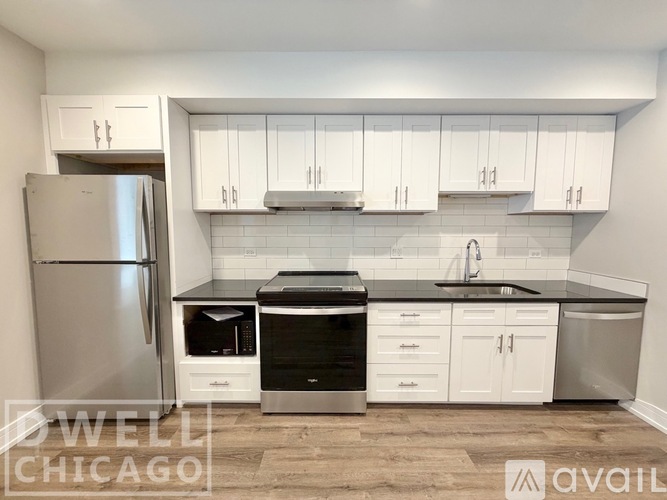 A kitchen with wood flooring and white cabinets.