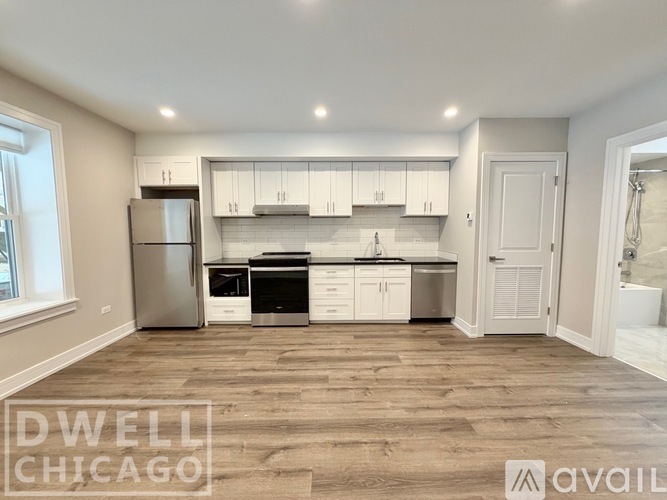A kitchen with white cabinets and a wooden floor.