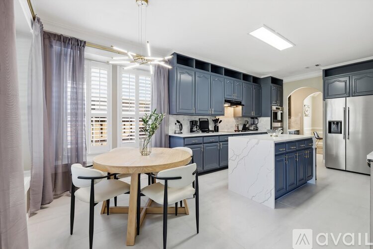 A modern kitchen with a round table and chairs in the center.