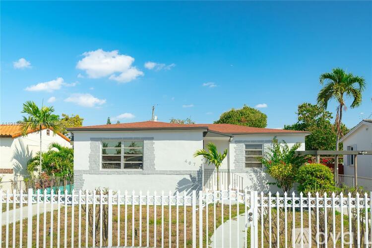 A white house with a red roof and a white picket fence.