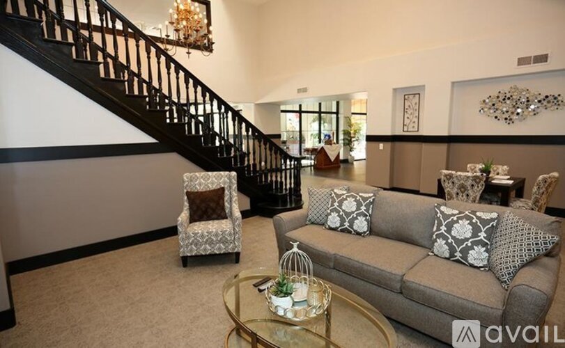 A living room with a grey couch and a glass coffee table.