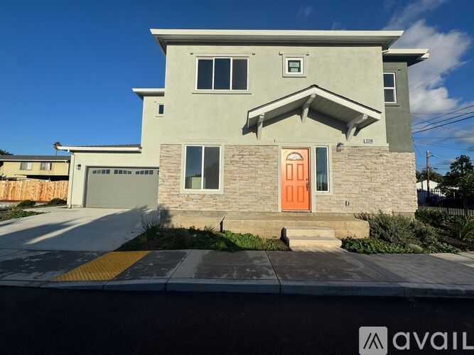 A house with a grey facade and a red door is for sale.