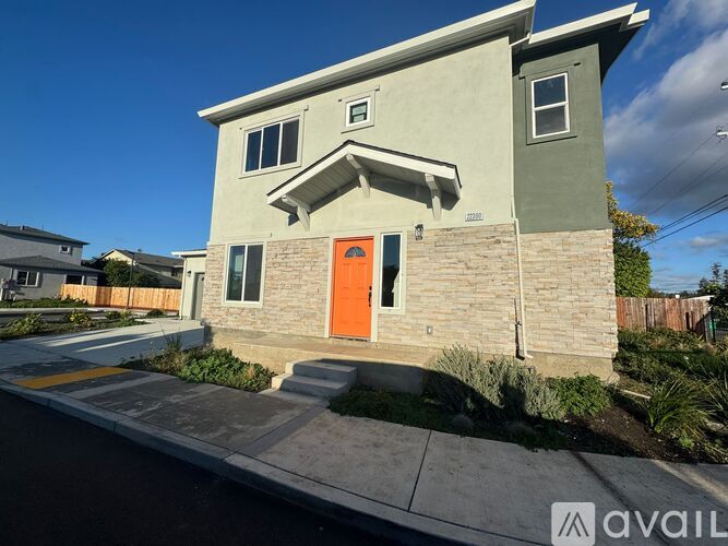A house with a grey and green exterior and an orange door.