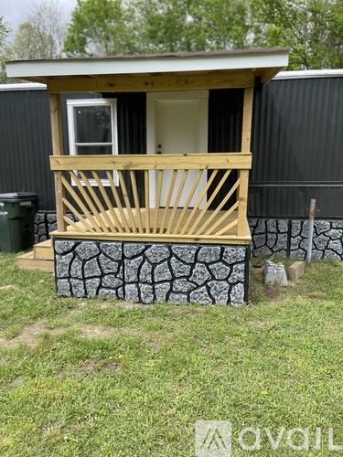 A small house with a wooden deck and a stone wall.