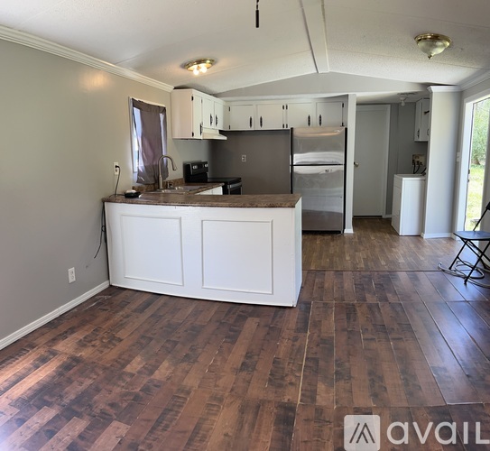 A kitchen with a wooden floor and white cabinets.