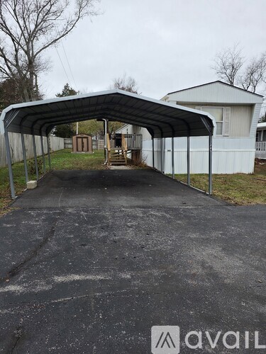 A covered driveway leads to a white house.