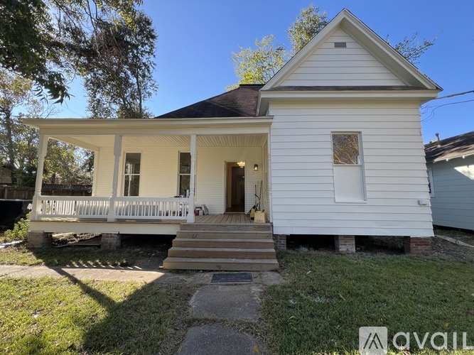 A small white house with a porch and a front door.