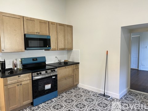 A kitchen with wooden cabinets and a black and white floor.