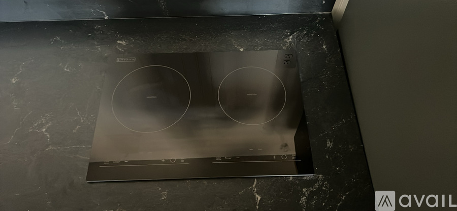A black stove top with two burners is installed in a kitchen.