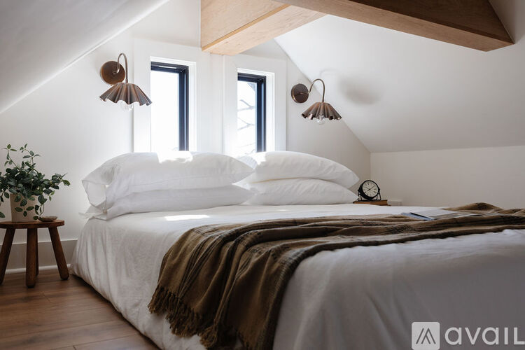 A bedroom with a large bed and a plant on a side table.