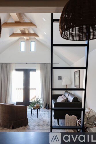 A living room with a brown armchair and a black shelf with a lamp on it.