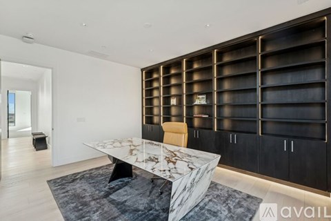 A modern dining room with a marble table and black shelving.