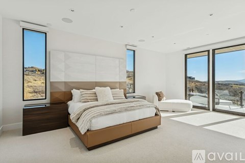 A bedroom with a large bed and a view of the outdoors through the windows.