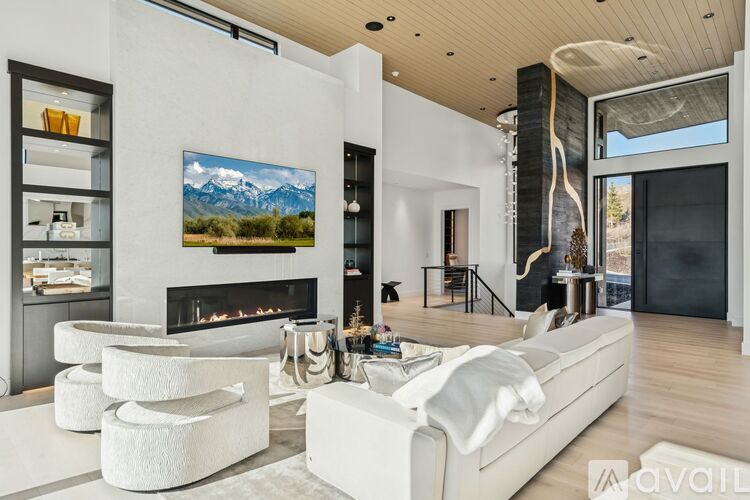 A modern living room with a fireplace and a painting of a mountain landscape on the wall.