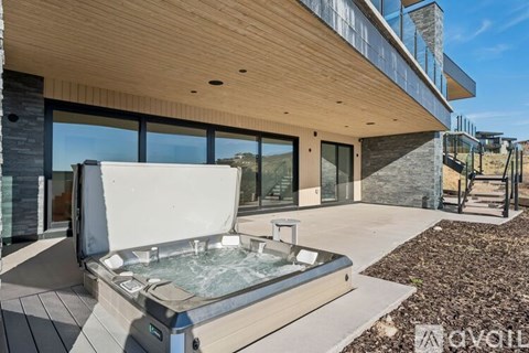 A hot tub is located on a patio outside of a modern house.