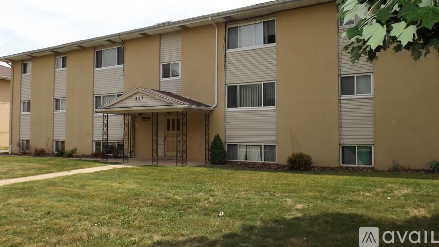 A beige apartment building with a grassy front yard.