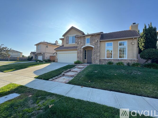 A house with a stone facade and a large front yard is shown.