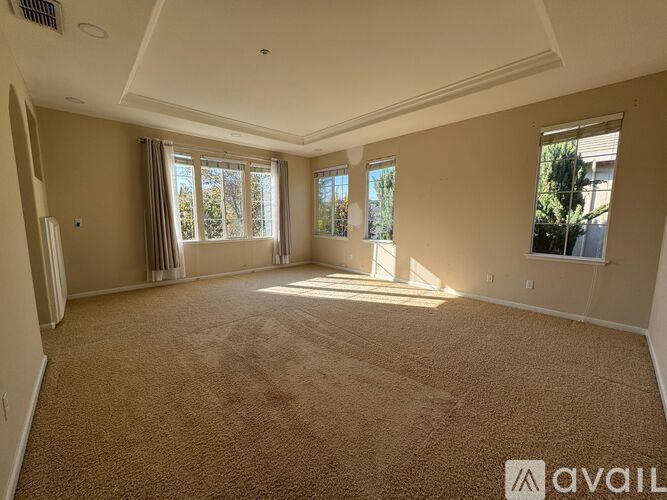 A spacious room with carpeted floor and large windows.