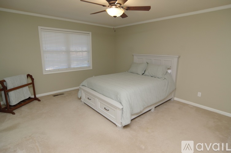 A bedroom with a white bed and a ceiling fan.