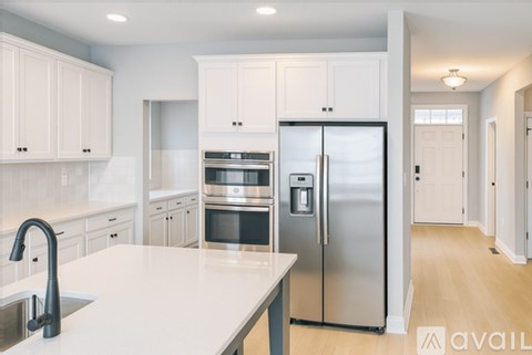 A modern kitchen with white cabinets and stainless steel appliances.