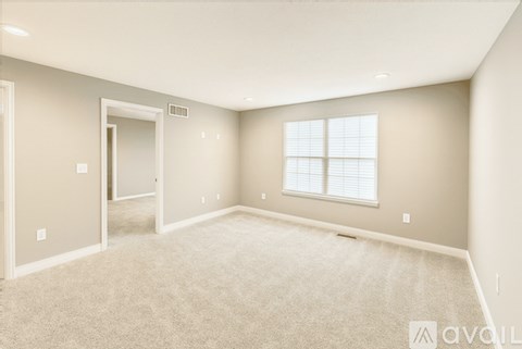 A spacious room with a carpeted floor and a window with blinds.