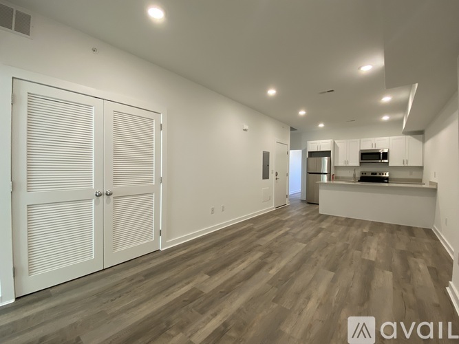 A spacious room with wood flooring and white walls.