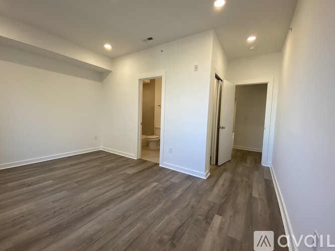 A spacious room with wood flooring and white walls.