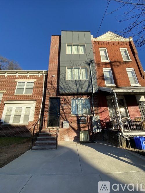 A modern building with a black facade is situated between two red brick buildings.