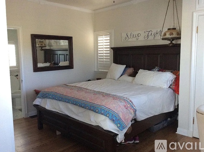 A bedroom with a bed, a mirror, and a sign above the bed that says "Sleep Tight".