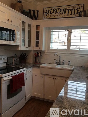 A kitchen with white appliances and cabinets with a sign that says Mercantile above the sink.