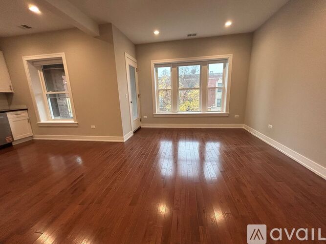 A room with wooden flooring and a window showing daylight outside.