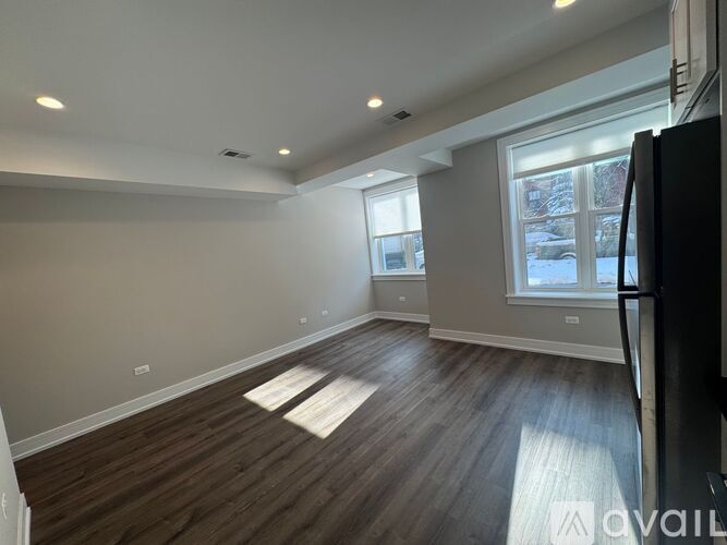 A spacious room with wooden flooring and a large window.