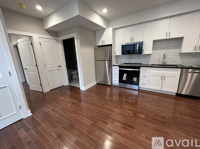 A kitchen with white cabinets and a wooden floor.