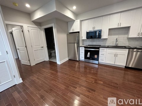 A kitchen with white cabinets and a wooden floor.