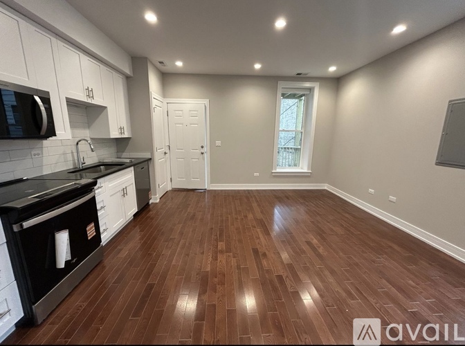 A kitchen with wooden floors and white cabinets.