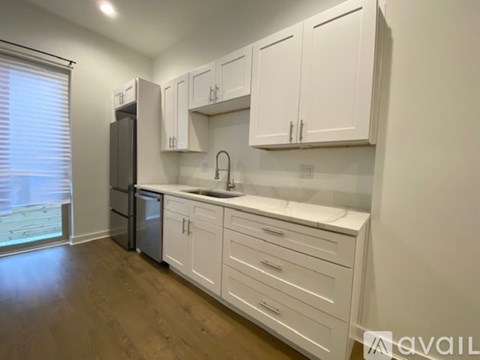 A kitchen with white cabinets and a black refrigerator.
