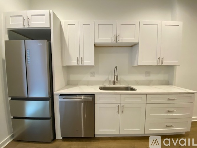 A kitchen with white cabinets and a stainless steel refrigerator.