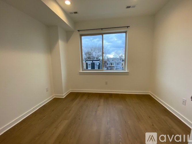 A room with wooden floors and a large window showing a view of buildings outside.