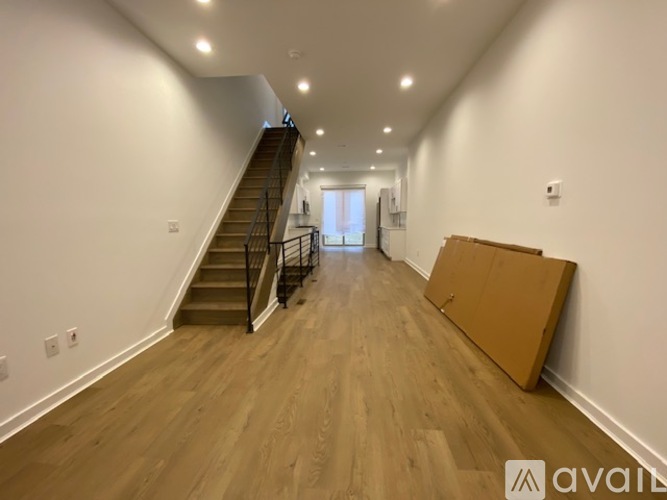A long hallway with a staircase and a box on the floor.