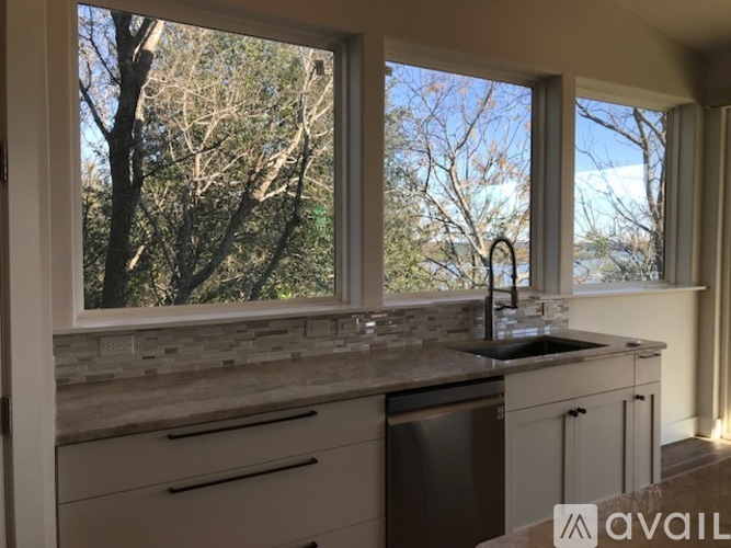 A kitchen with a sink and a window overlooking trees.