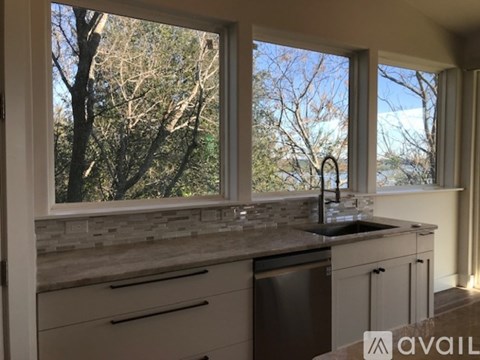 A kitchen with a sink and a window overlooking trees.