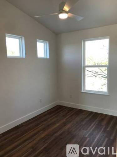 A room with wooden floors and three windows.