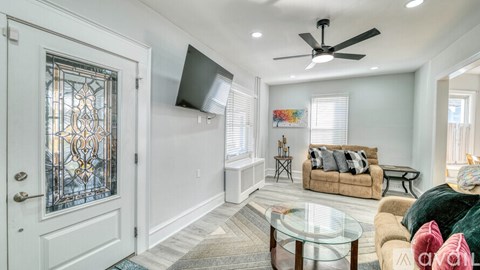 A living room with a brown couch, a black coffee table, and a flat screen TV mounted on the wall.
