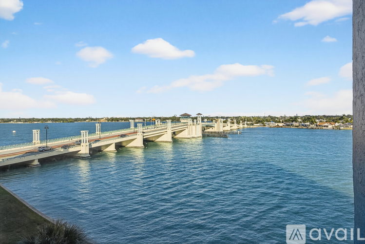 A bridge spans across a calm body of water under a clear blue sky.