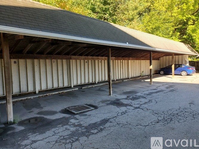 A blue car is parked in a garage with a wooden roof.