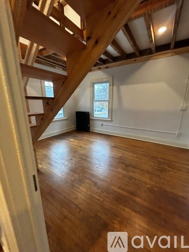 A room with wooden floors and a window with a view of trees outside.