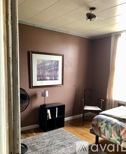 A bedroom with a bed, chair, and painting on the wall.